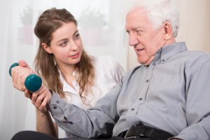 Physical therapist with senior using dumbbells